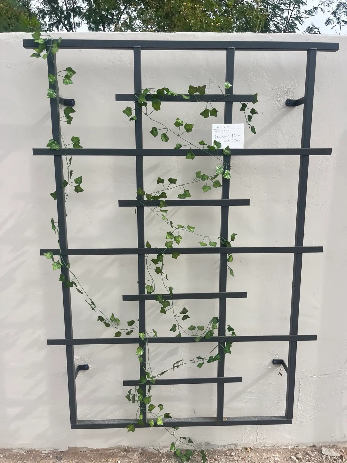 Charcoal ladder-grid wall trellis mounted on white stucco by A1 Trellis